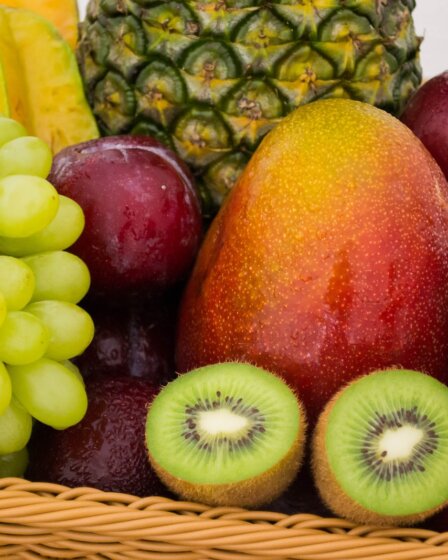 red apple fruit beside green apple and yellow fruit on brown woven basket