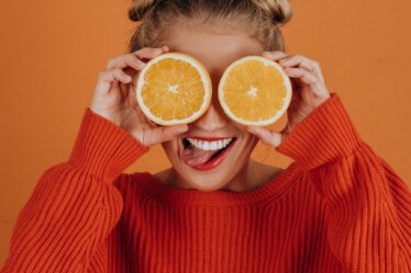 woman in red knit sweater holding lemon