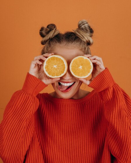 woman in red knit sweater holding lemon