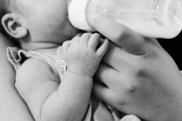 grayscale photo of baby feeding