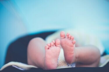 shallow focus photography of baby wearing white diaper lying