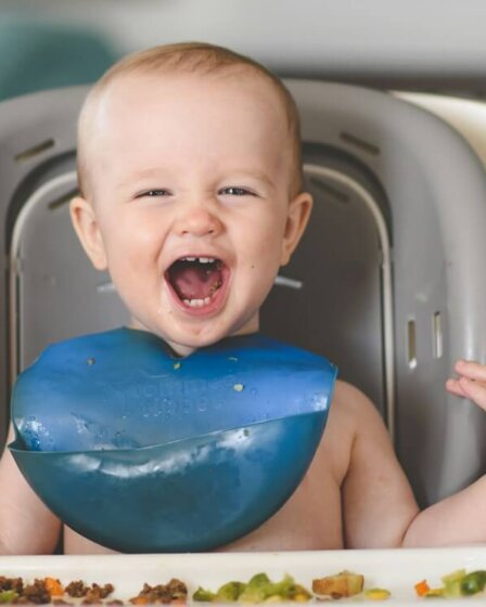 baby lying on white and blue bathtub